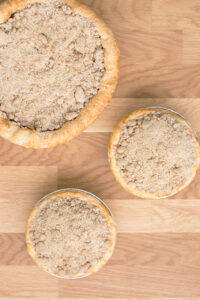 Three pies sit on a wood countertop