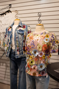 A decorated denim jacket and a top with 3-D flowers are worn by mannequins