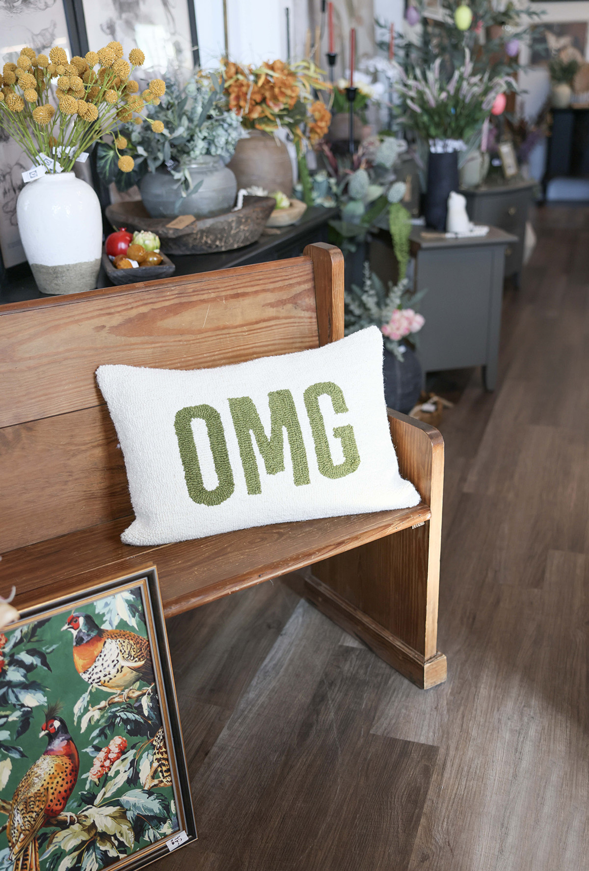 An "OMG" pillow on a bench at RQ Designs